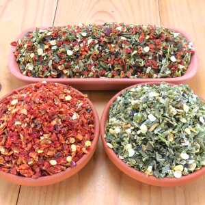 Drei Tonschalen mit jeweils verschieden farbigen Jalapeno-Chili geschrotet. In Rot, Grün und in rot-grüner Mischung.