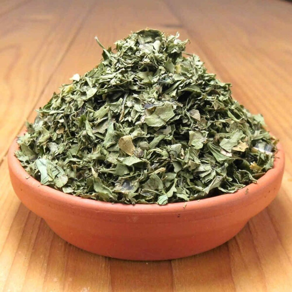 Getrocknete Korianderblätter gerebelt, auch Cilantro genannt, in einer Tonschale.