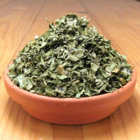 Getrocknete Korianderblätter gerebelt, auch Cilantro genannt, in einer Tonschale.